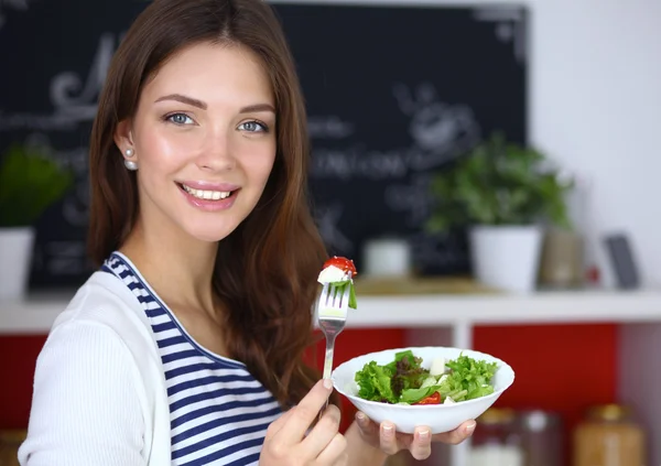 Giovane donna mangiare insalata e tenere un'insalata mista — Foto Stock