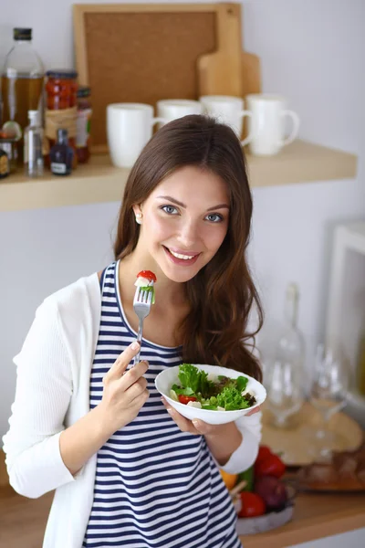 Junge Frau isst Salat und hält einen gemischten Salat in der Hand — Stockfoto