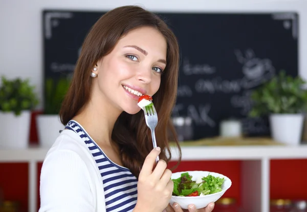 Mujer joven comiendo ensalada y sosteniendo una ensalada mixta — Foto de Stock