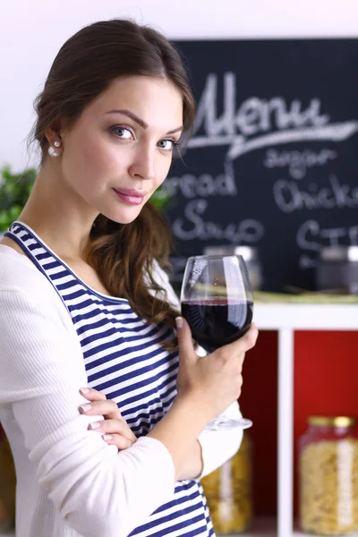 Flot kvinde drikker noget vin hjemme i køkkenet - Stock-foto