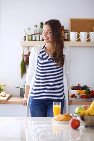 Ung kvinna med glas juice och kakor stående i köket — Stockfoto