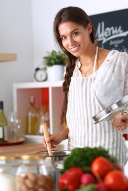 Mutfakta ahşap kaşıkla yemek pişiren kadın