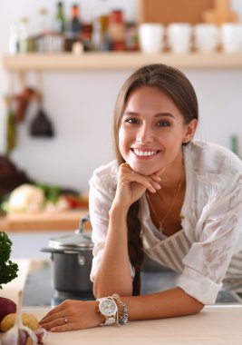 Mutfakta masanın yanında duran genç bir kadın.