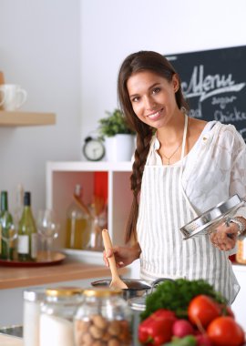 Mutfakta ahşap kaşıkla yemek pişiren kadın