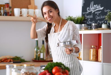 Mutfakta ahşap kaşıkla yemek pişiren kadın