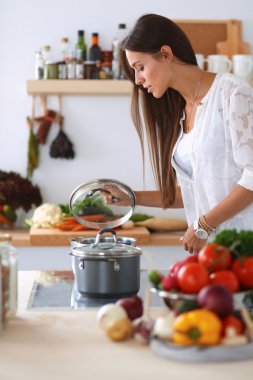 Mutfakta sobanın yanında duran genç bir kadın.