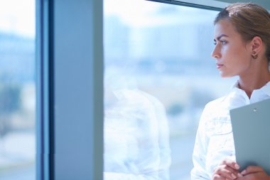 Belgeleri elinde tutan ofis pencere karşı ayakta işkadını