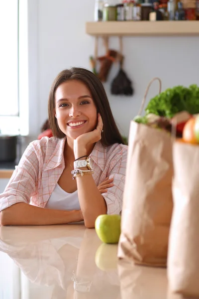 Jovem mulher sentada ao lado da mesa na cozinha — Fotografia de Stock