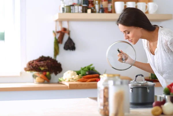 Young woman standing by the stove in the kitchen