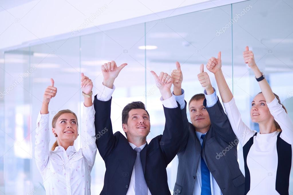 Happy business team showing thumbs up in office