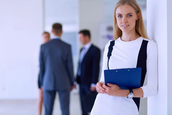 Portrait of young businesswoman in office with colleagues in the background — Stock Photo, Image