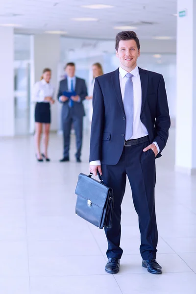 Porträt eines jungen Geschäftsmannes im Amt mit Kollegen im Hintergrund — Stockfoto