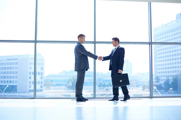 Full length image of two successful business men shaking hands with each other