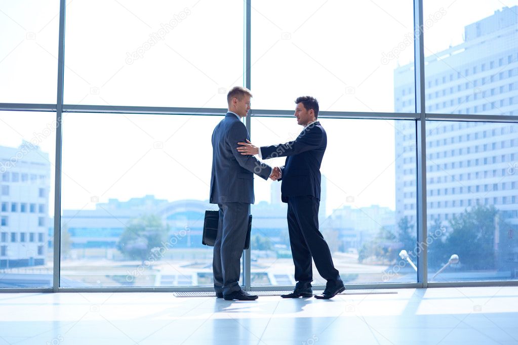 Full length image of two successful business men shaking hands with each other