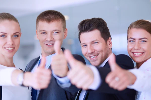 Feliz equipo de negocios mostrando pulgares hacia arriba en la oficina — Foto de Stock