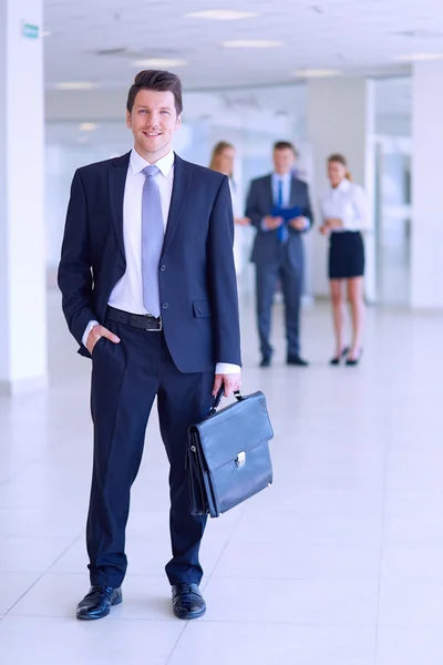 Porträtt av ung affärsman i office med kollegor i bakgrunden — Stockfoto