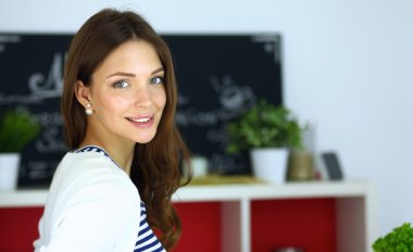 Genç bir kadın mutfakta duruyor.