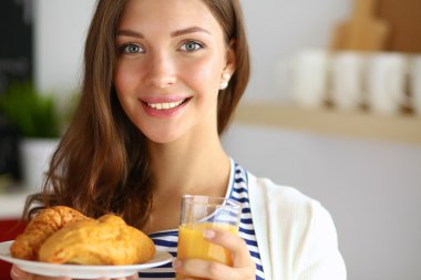 Bir bardak meyve suyu ve keki olan genç bir kadın.