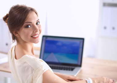 Masasında dizüstü bilgisayarla oturan bir iş kadınının portresi.