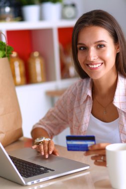 Gülümseyen kadın mutfakta tablet ve kredi kartı kullanarak alışveriş online