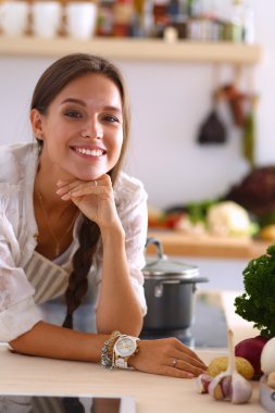 Mutfakta yemek yapmak için tablet bilgisayar kullanan genç bir kadın.
