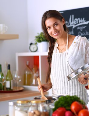 Mutfakta ahşap kaşıkla yemek pişiren kadın