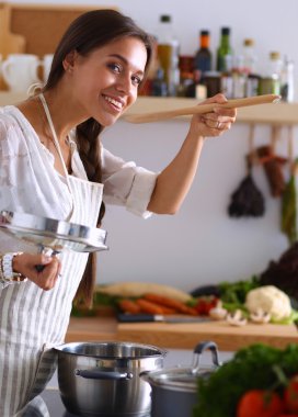 Mutfakta ahşap kaşıkla yemek pişiren kadın