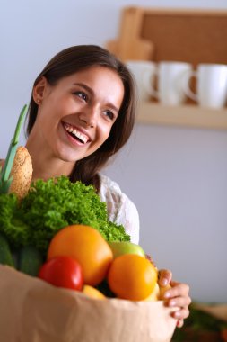 Elinde sebzeli alışveriş torbası tutan genç bir kadın. 