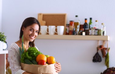 Elinde sebzeli alışveriş torbası tutan genç bir kadın. 