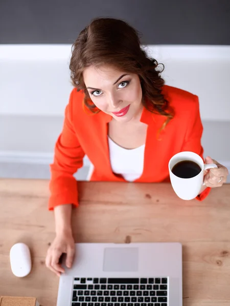 Mulher atraente sentada na mesa no escritório, trabalhando com computador portátil — Fotografia de Stock