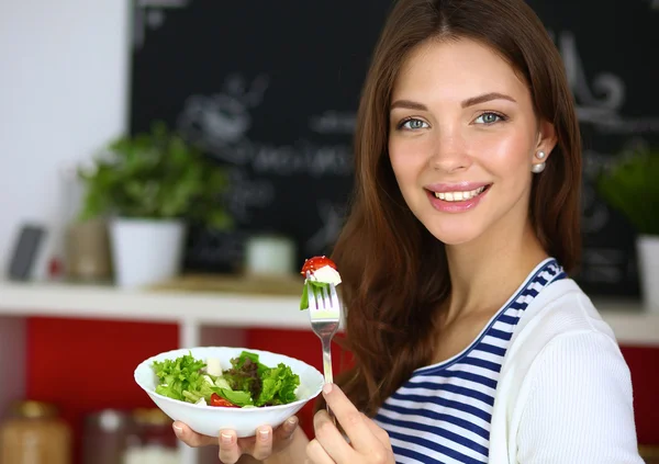 Jovem comendo salada e segurando uma salada mista — Fotografia de Stock