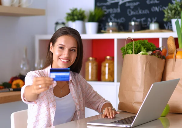 Smiling woman online shopping using tablet and credit card in kitchen — Stock Photo, Image