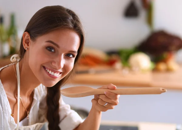 Mujer cocinera en cocina con cuchara de madera —  Fotos de Stock