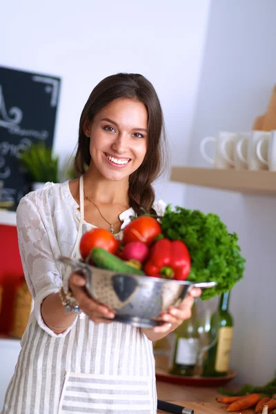 Lächelnde junge Frau mit Gemüse in der Küche — Stockfoto