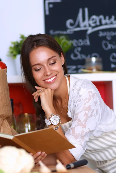 Giovane donna che legge il libro di cucina, alla ricerca di ricetta — Foto Stock