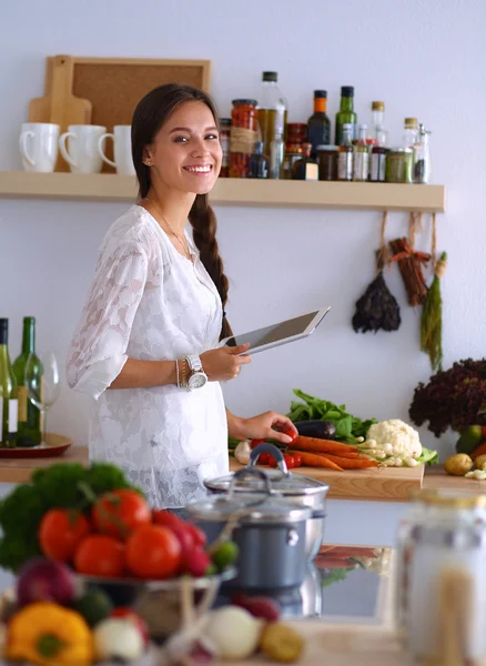 Mujer joven usando una tableta para cocinar en su cocina —  Fotos de Stock