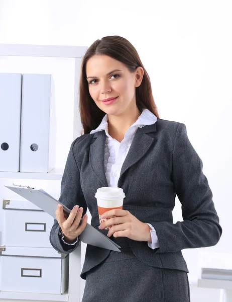 Atrakcyjna młoda bizneswoman stojąca przy biurku z folderem w biurze — Zdjęcie stockowe