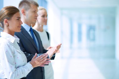 Gülümseyen iş adamları ofiste iyi bir sunumu alkışlıyorlar.