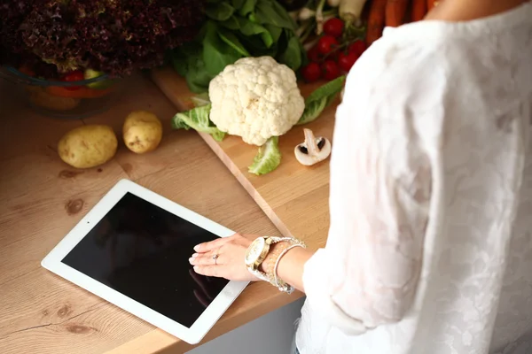 Giovane donna che utilizza un tablet per cucinare nella sua cucina — Foto Stock