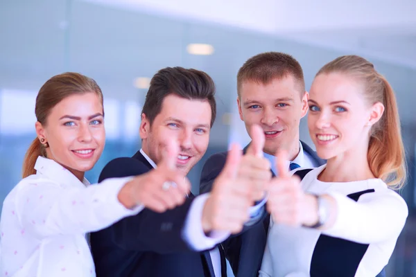 Счастливая бизнес-команда, демонстрирующая большие пальцы в офисе — стоковое фото