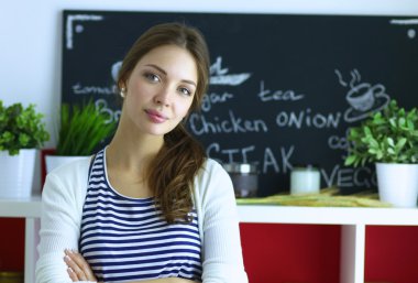 Genç bir kadın mutfakta duruyor.