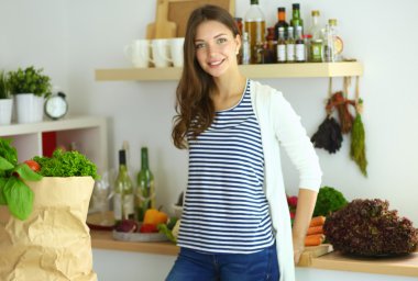 Genç bir kadın mutfakta duruyor.