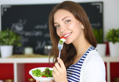 Salata yemek ve karışık salata tutan genç kadın 