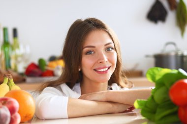 Mutfakta masanın yanında duran genç bir kadın.