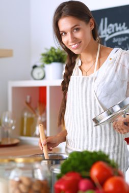 Mutfakta ahşap kaşıkla yemek pişiren kadın