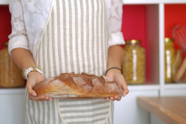 Genç bir kadın mutfağında lezzetli taze ekmek tutuyor.