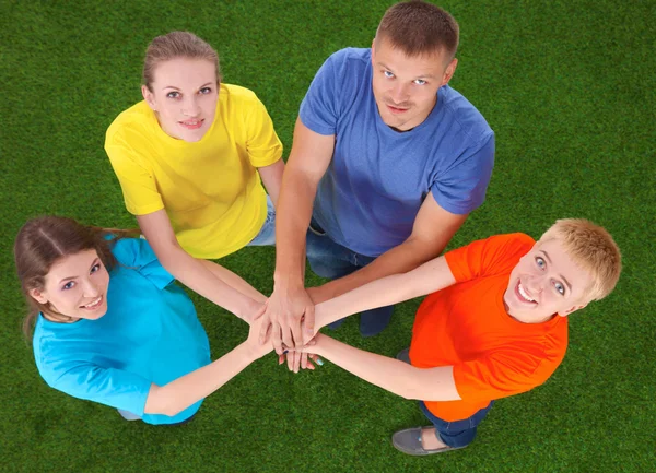 Lidé spojení jejich ruce na zelené trávě — Stock fotografie