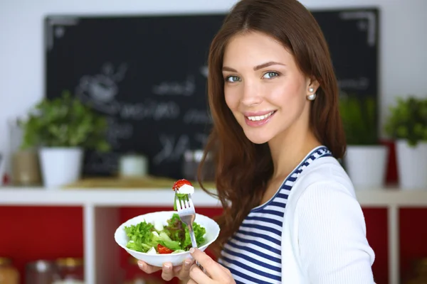Junge Frau isst Salat und hält einen gemischten Salat in der Hand — Stockfoto
