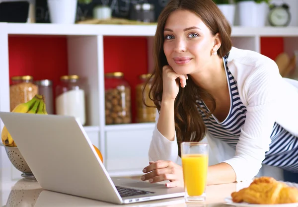Vonzó fiatal nő használ laptop, és ült a konyhában — Stock Fotó