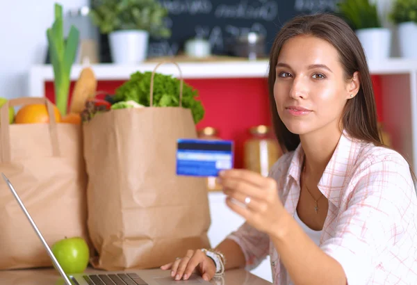 Посміхнена жінка онлайн покупки за допомогою планшета і кредитної картки на кухні — стокове фото